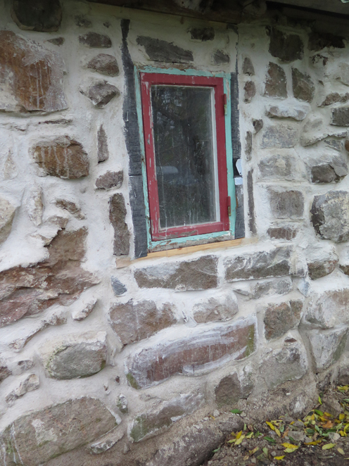 Resturerat fönster om stenvägg